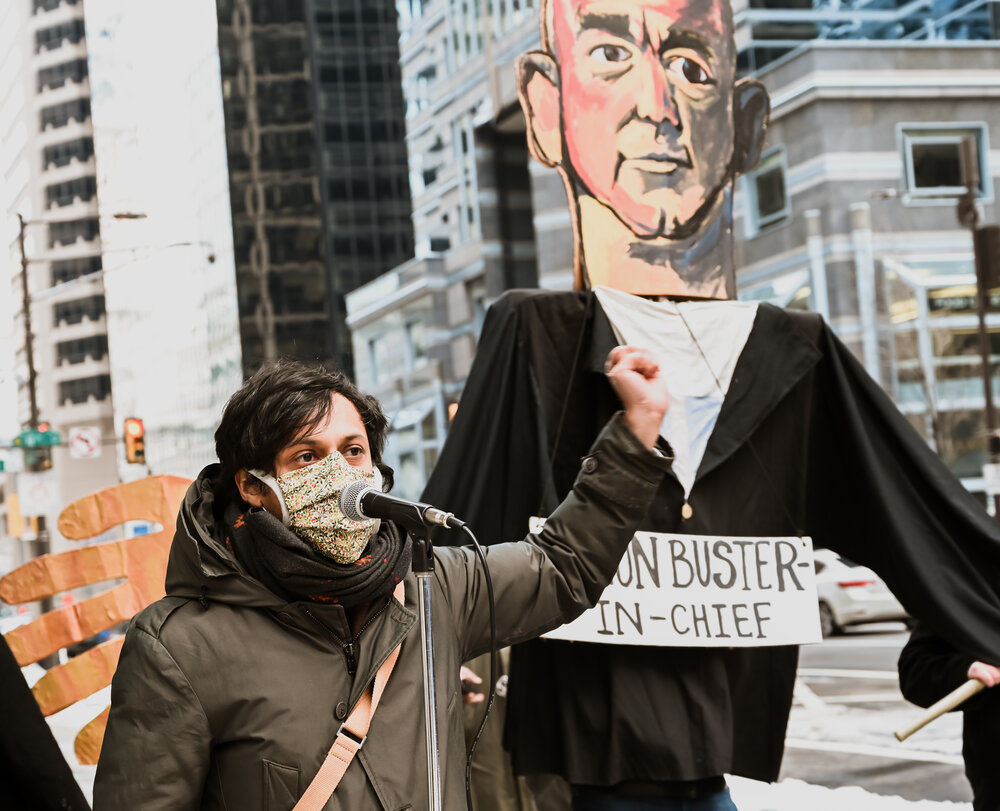 Photo by Joe Piette. Amazon worker addressing crowd in front of effigy of Jeff Bezos.